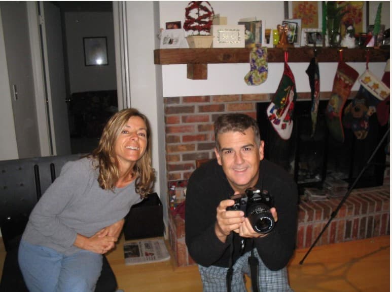 Hunter's mom and dad by the fireplace, dad holding a Canon film camera