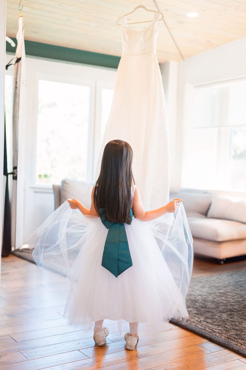 Flower girl twirling tulle dress below hanging wedding gown