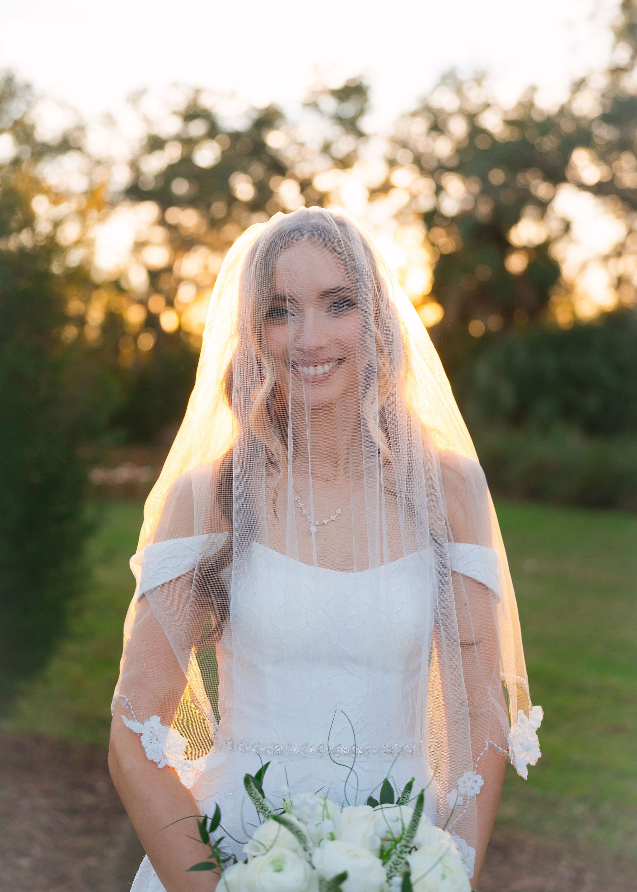 Bride smiling sheer veil sunset bokeh