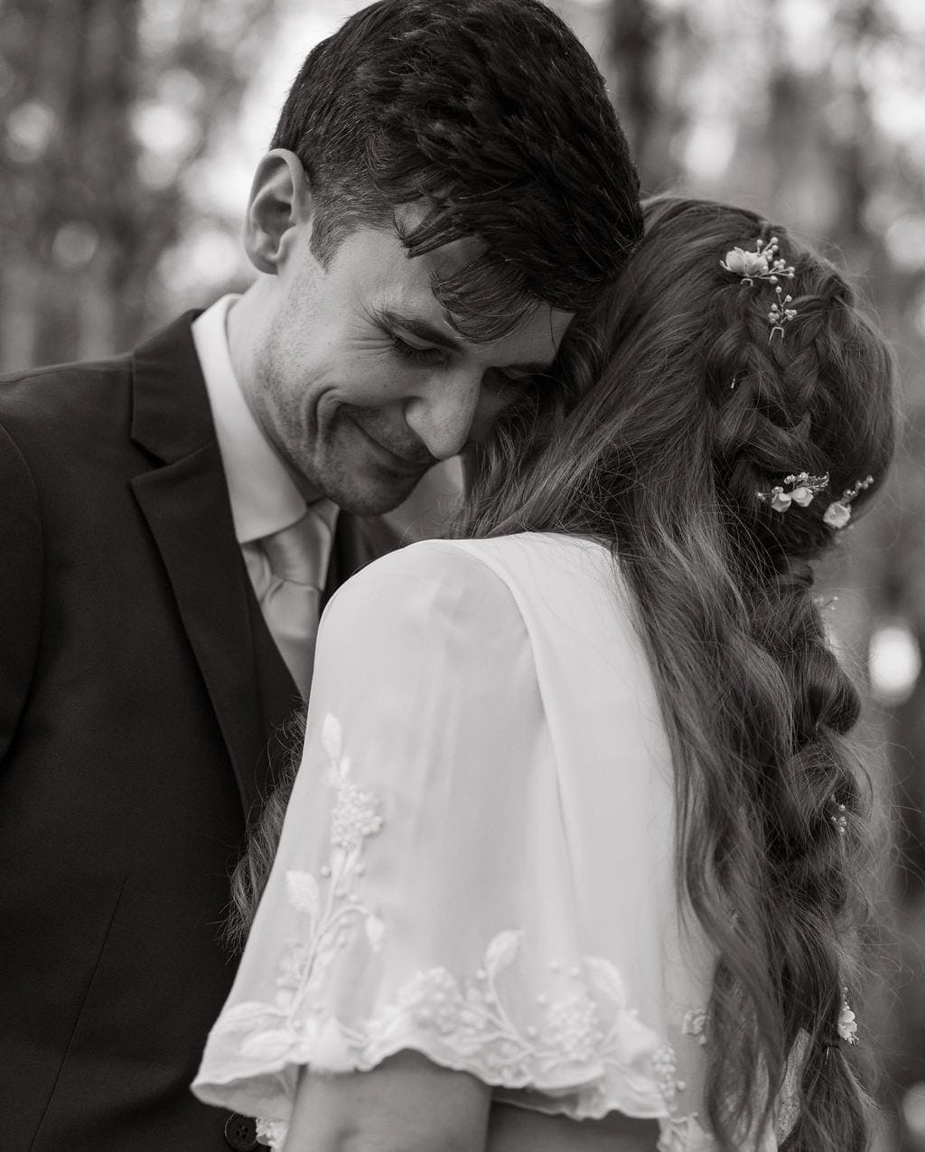 Black and white groom embracing bride braided hair flowers
