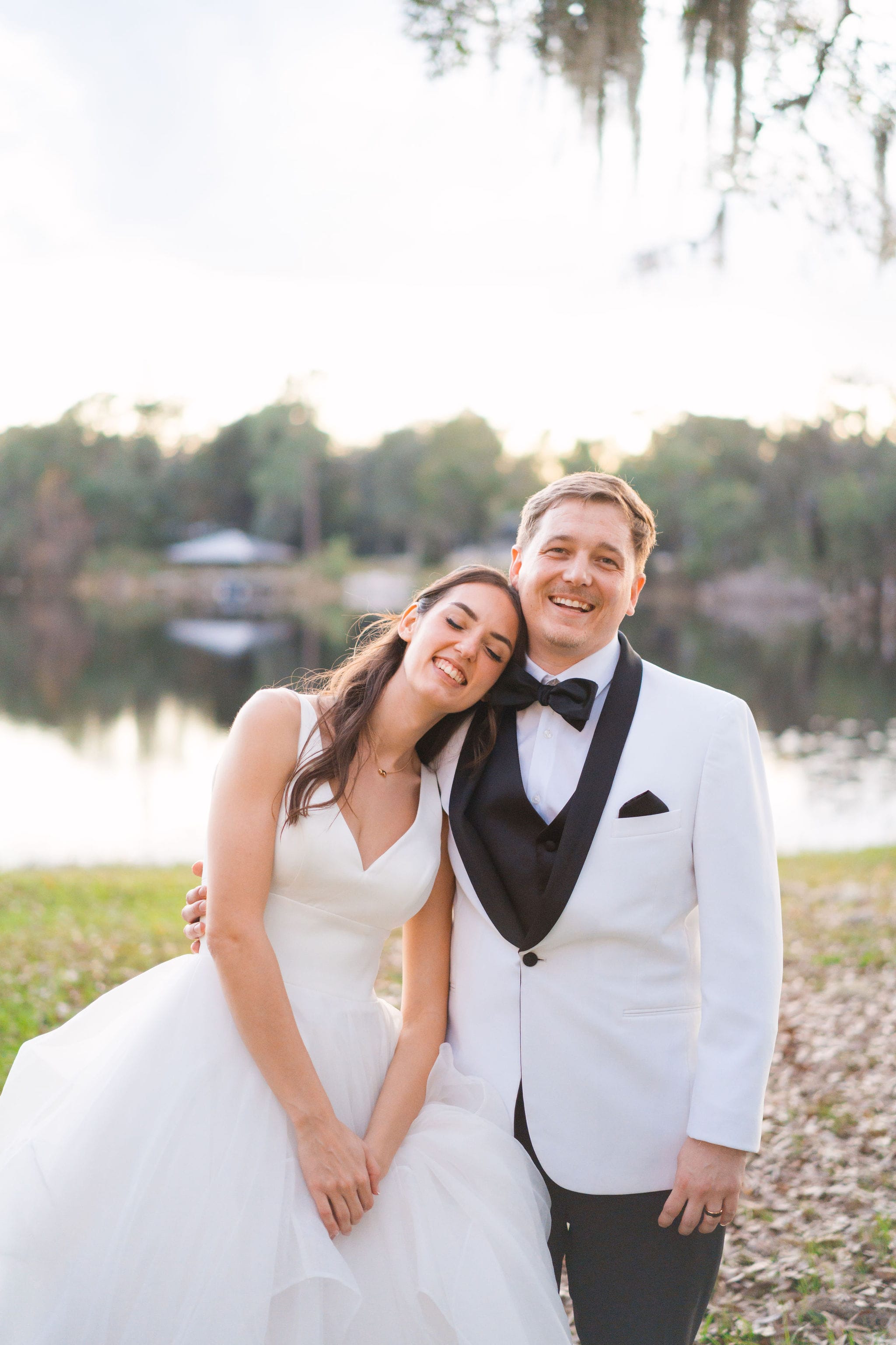 Lakeside bride head on grooms shoulder dusk