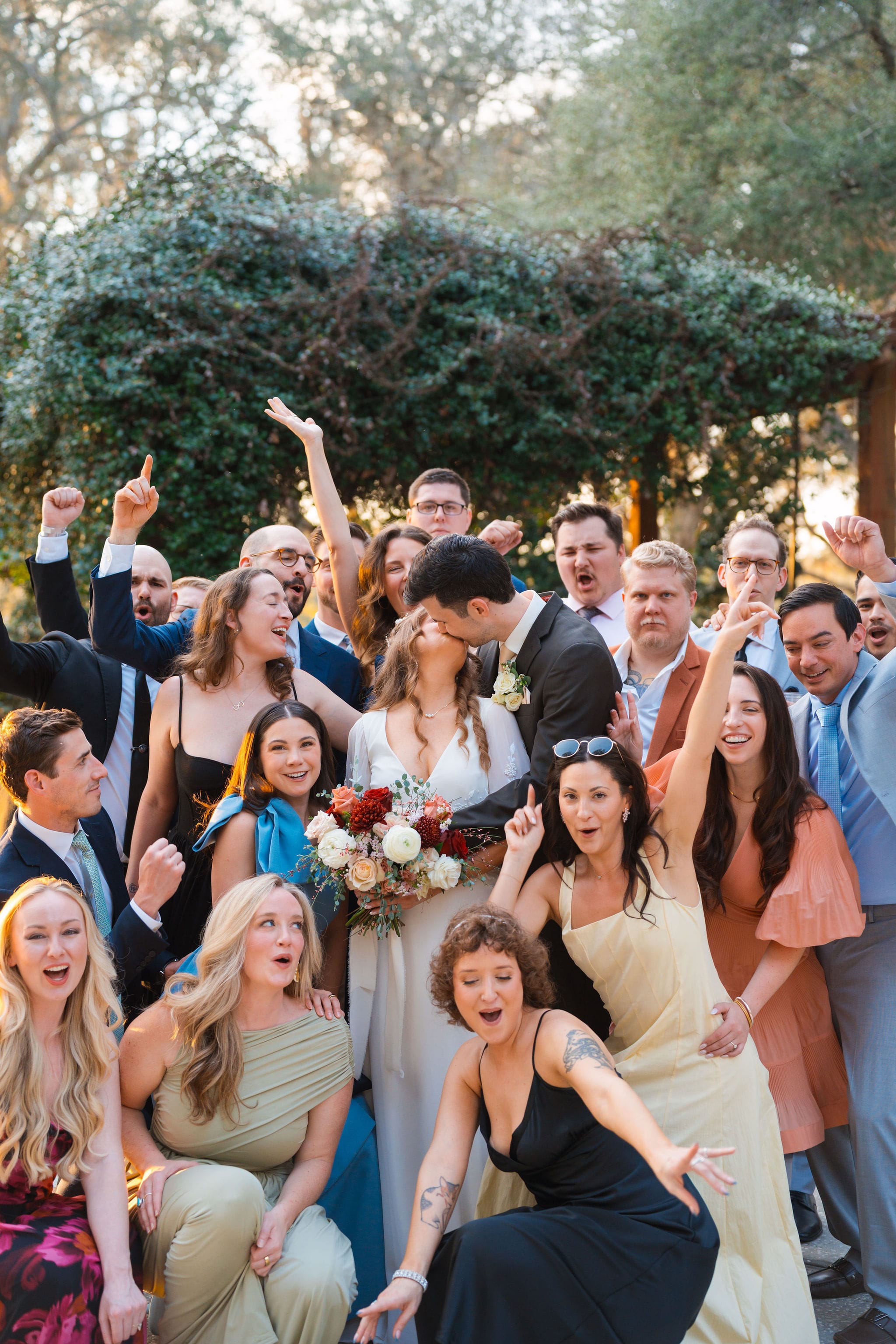 Newlyweds kissing amid wedding party garden