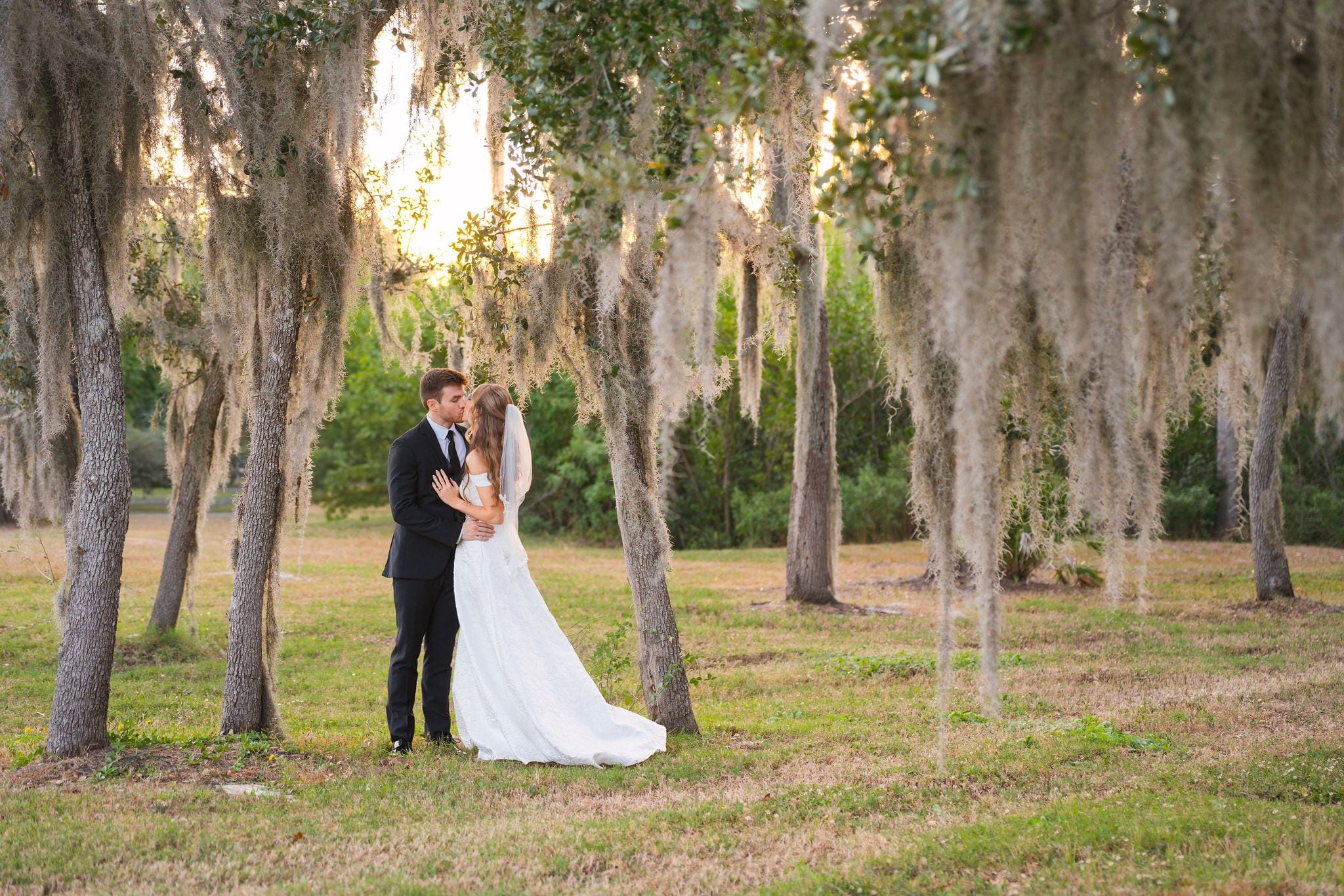 Newlyweds kiss spanish moss oaks golden hour