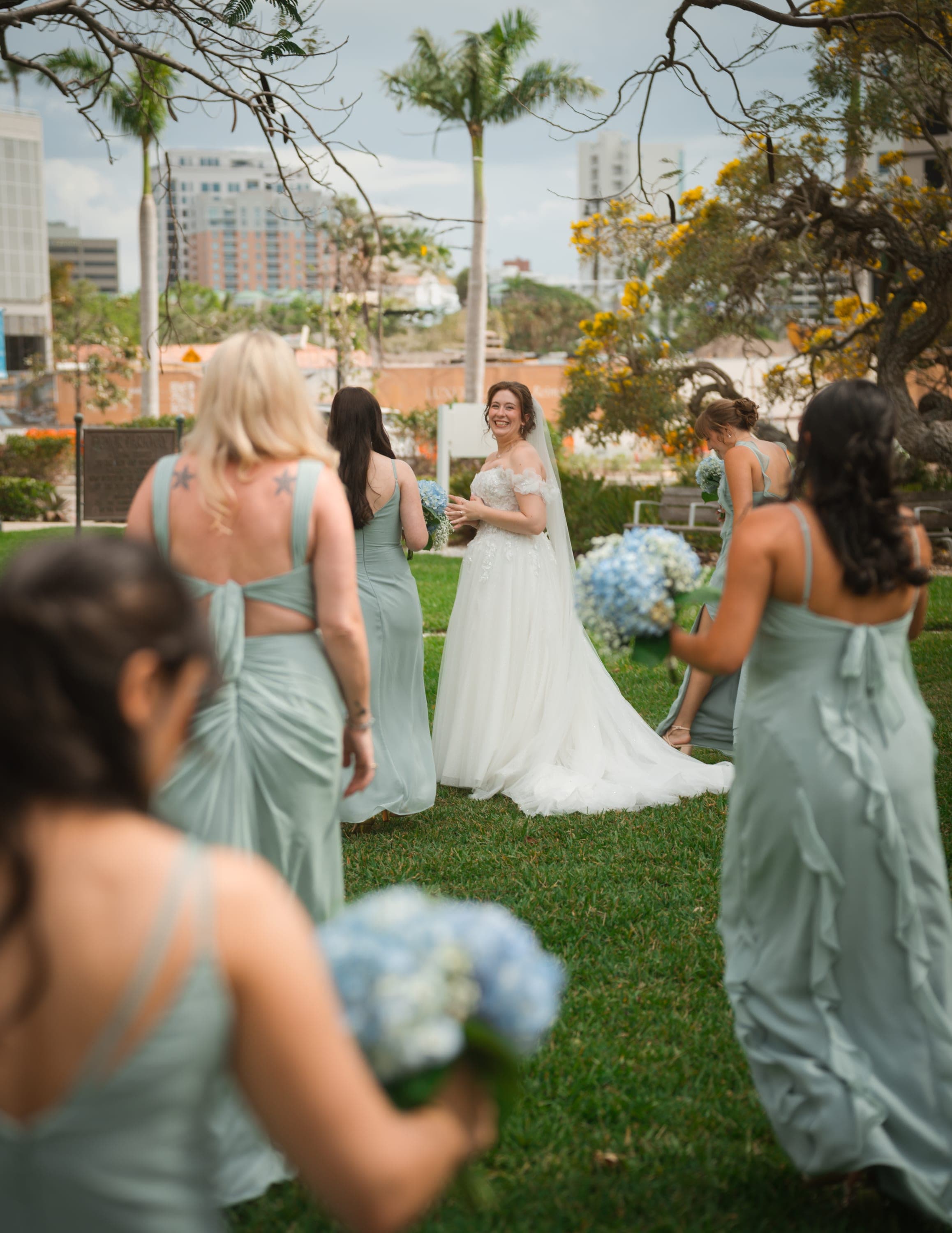Laughing bride looking back at her bridesmaids with the Tampa skyline behind
