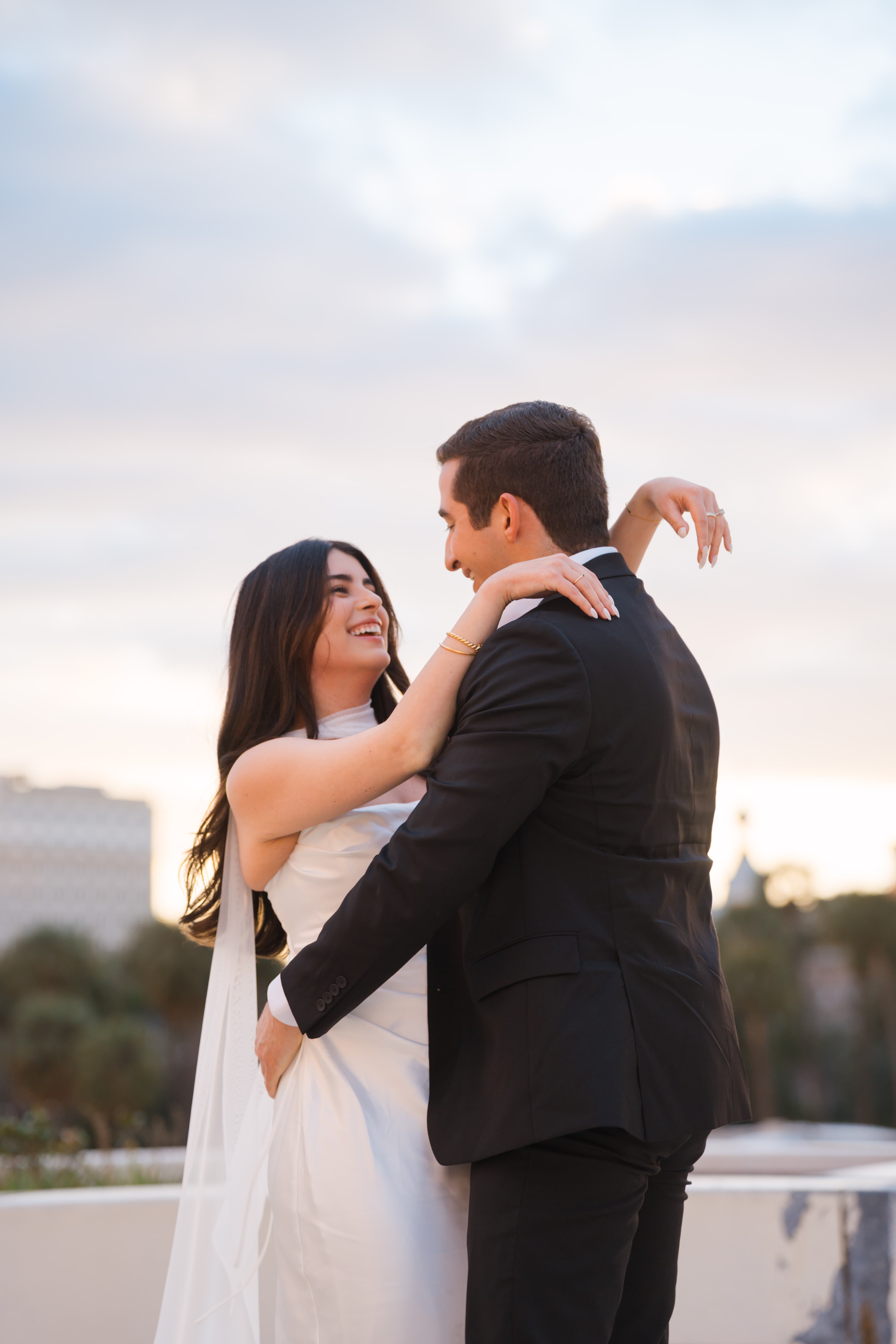 Bride laughing up at groom on a rooftop at sunset in Tampa