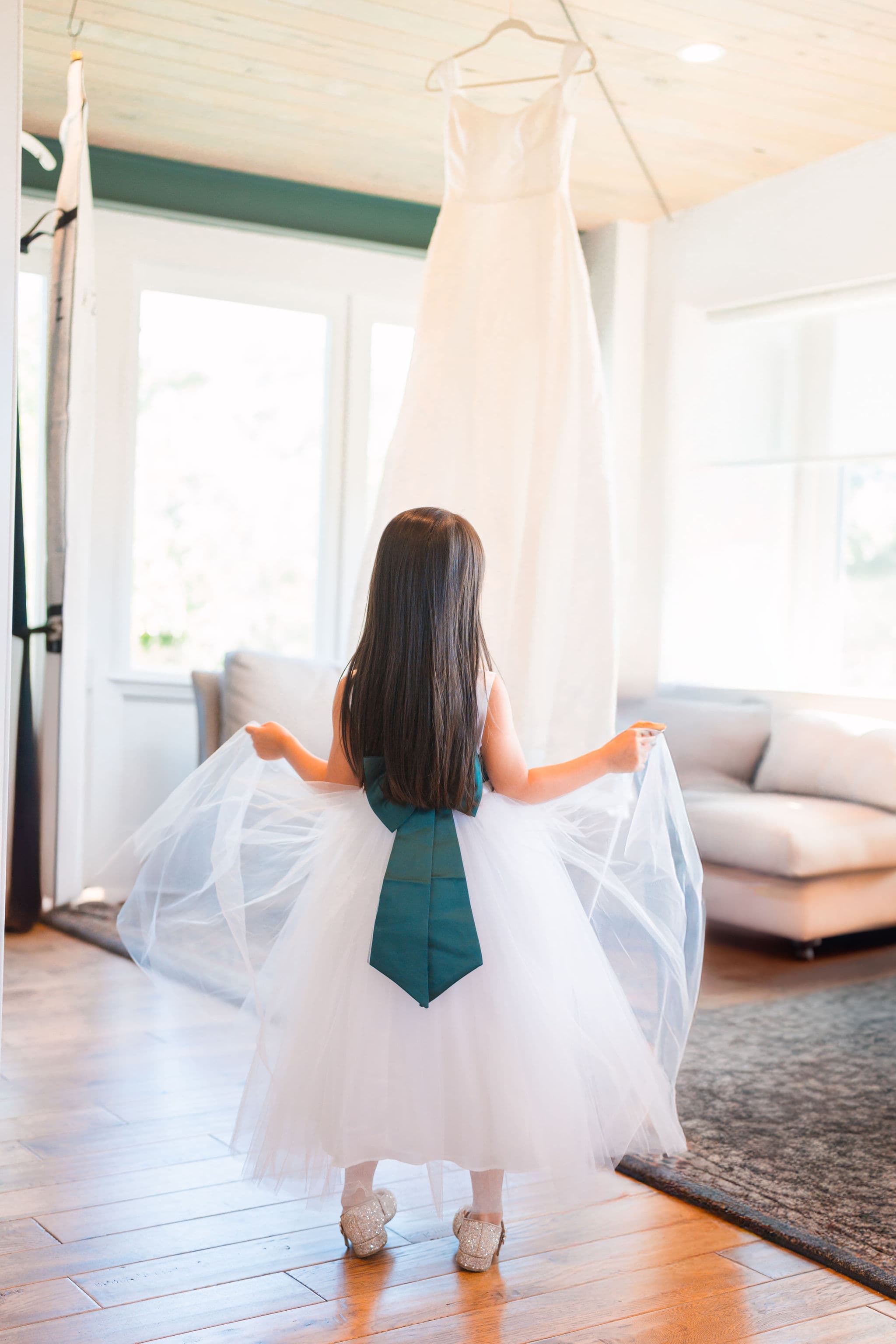 Flower girl gazing up at a hanging bridal gown