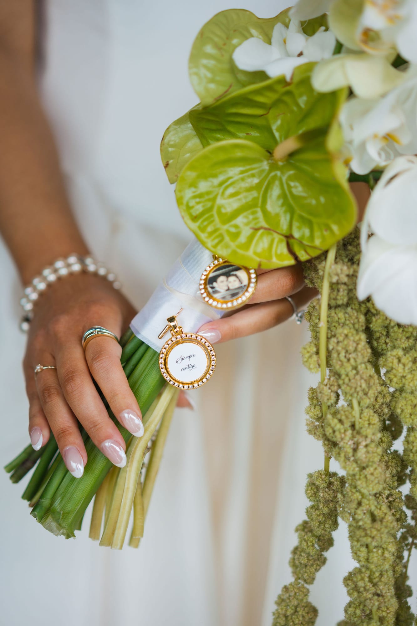 Bridal bouquet detail with a memorial charm attached to the stems