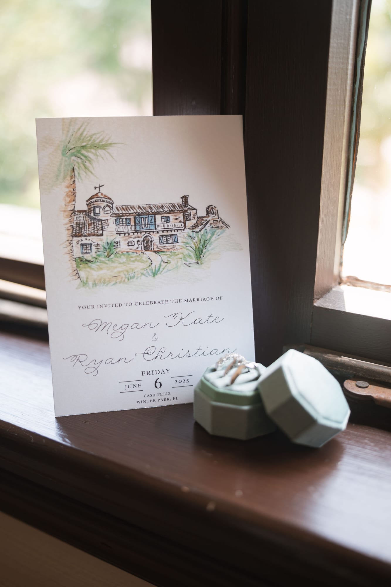 Wedding invitation and ring boxes arranged on a windowsill in natural light