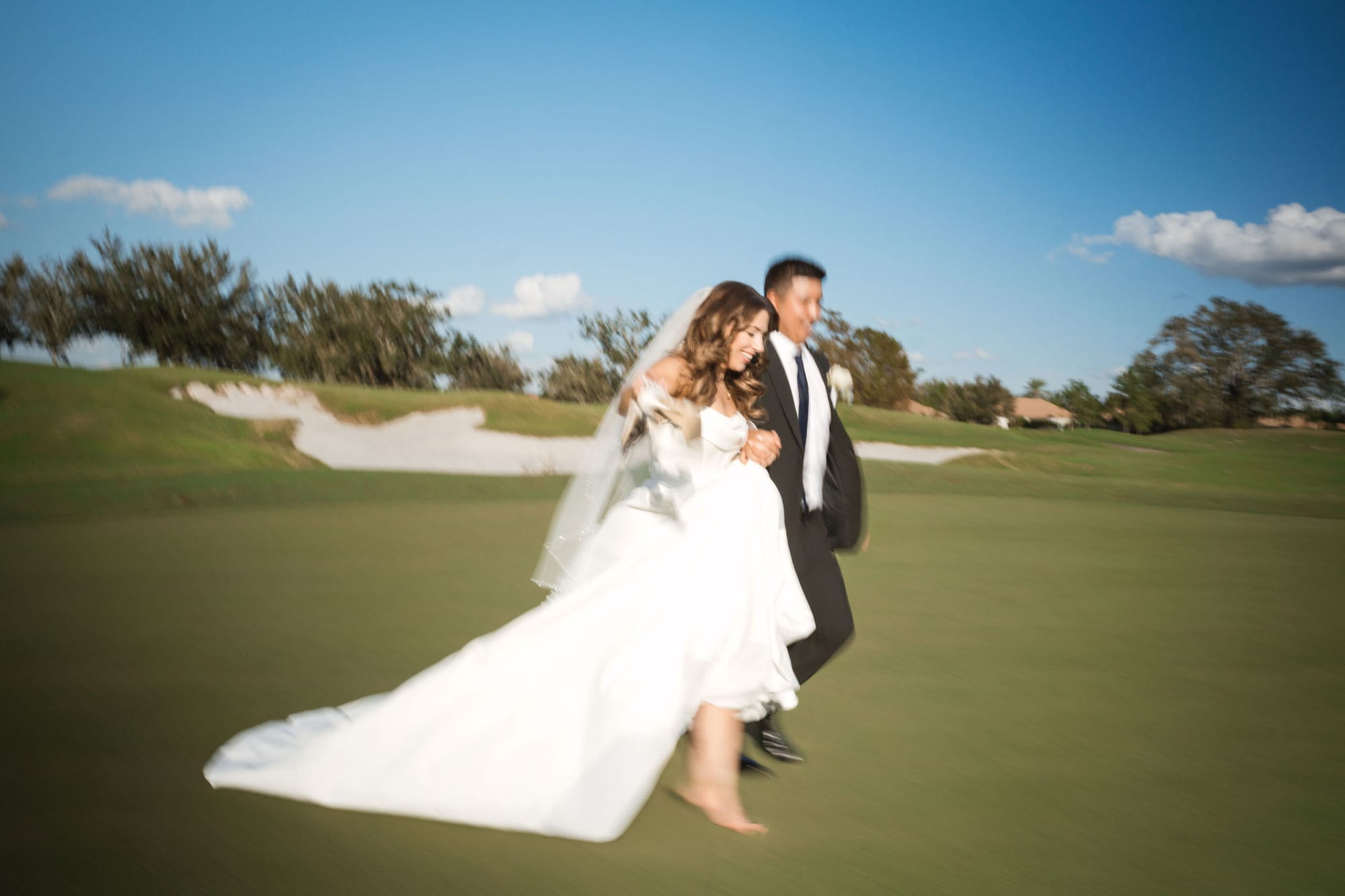 Bride and groom walking the golf course fairway lined with palm trees