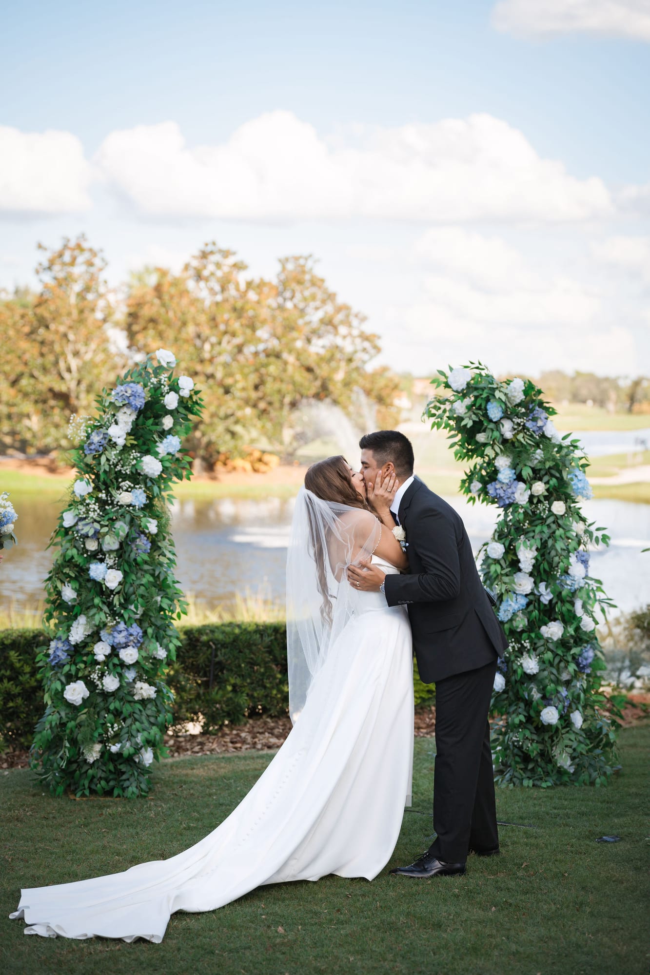 Bride and groom share their first kiss under the floral arch