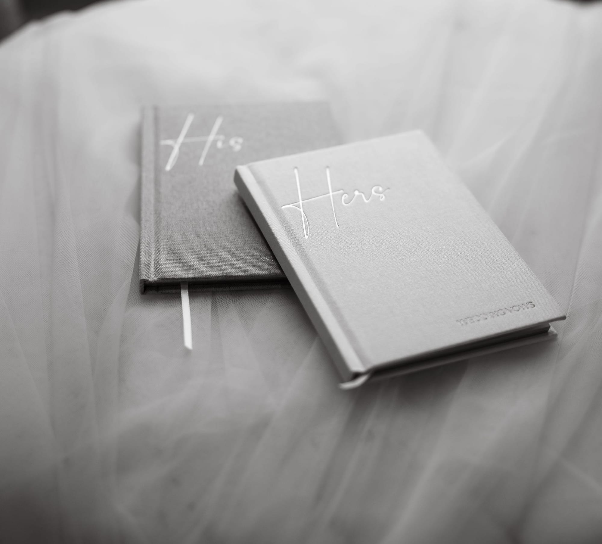 His and Hers vow books resting on a bed before the wedding