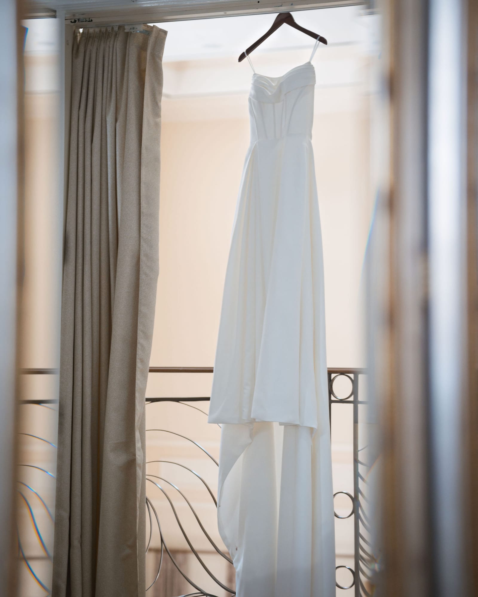 Wedding dress hanging in a window with soft morning light
