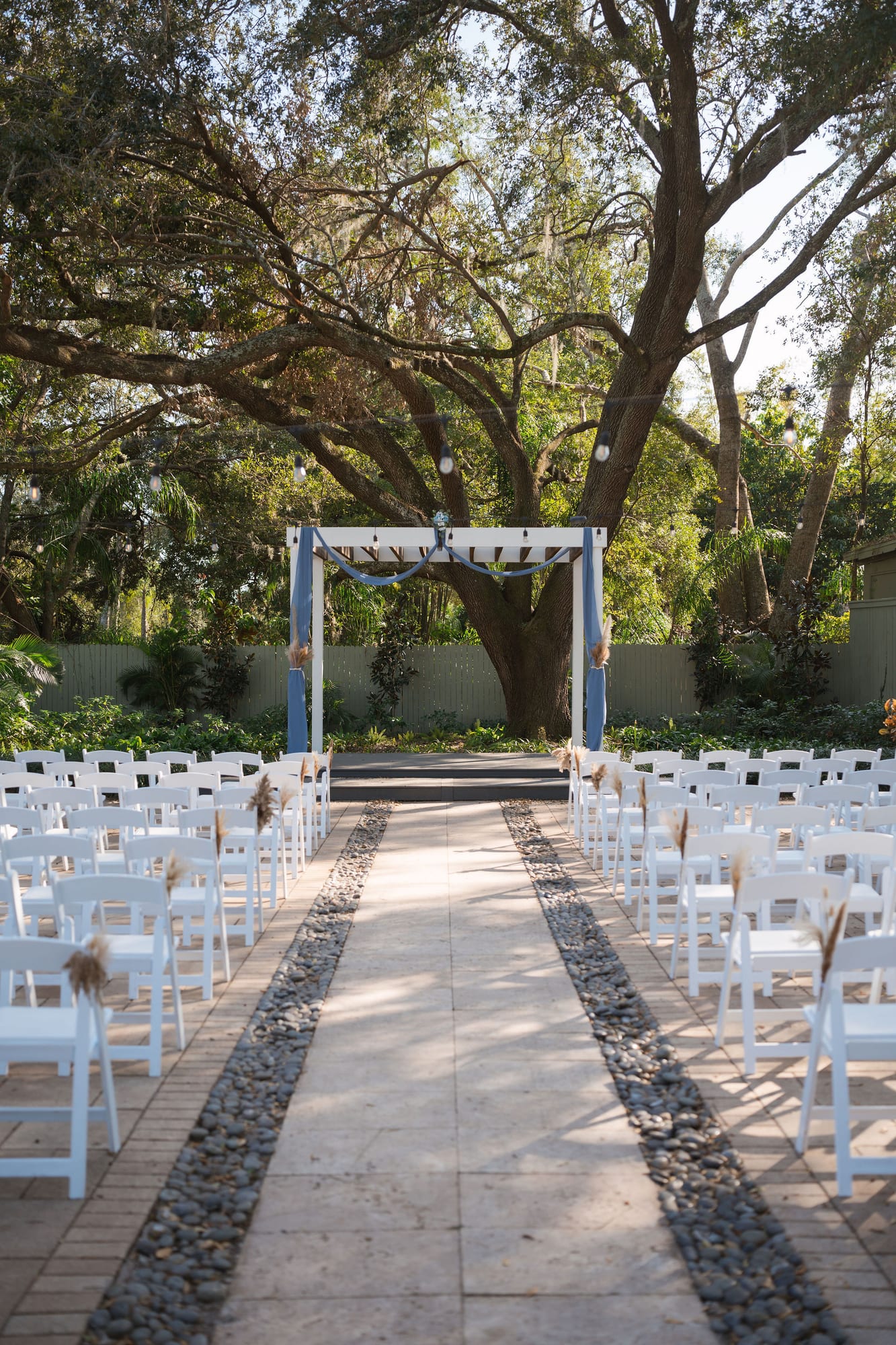Empty ceremony aisle and draped pergola under the live oak canopy at SoireEstate