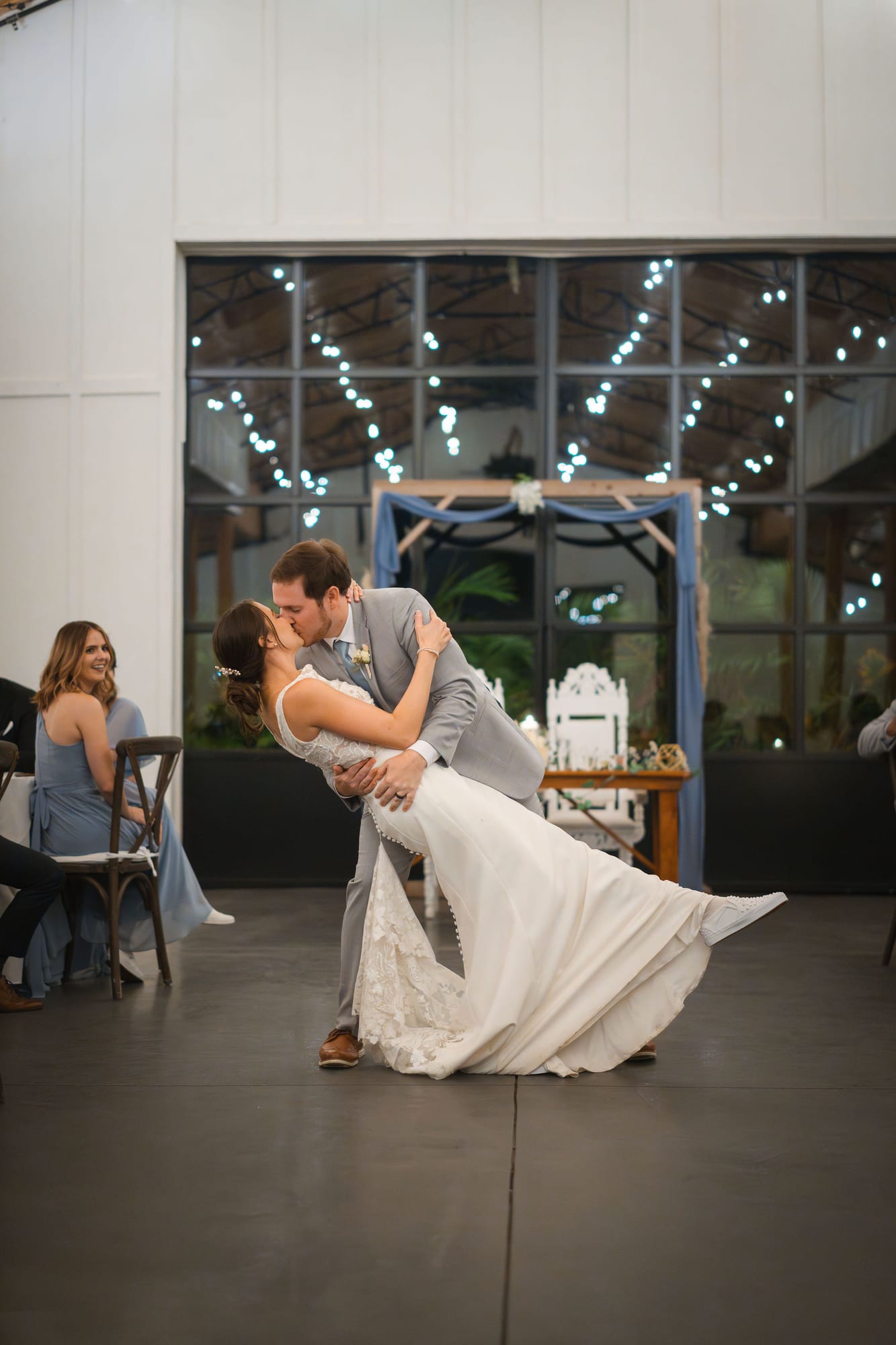 Groom dipping his bride during their first dance under string lights
