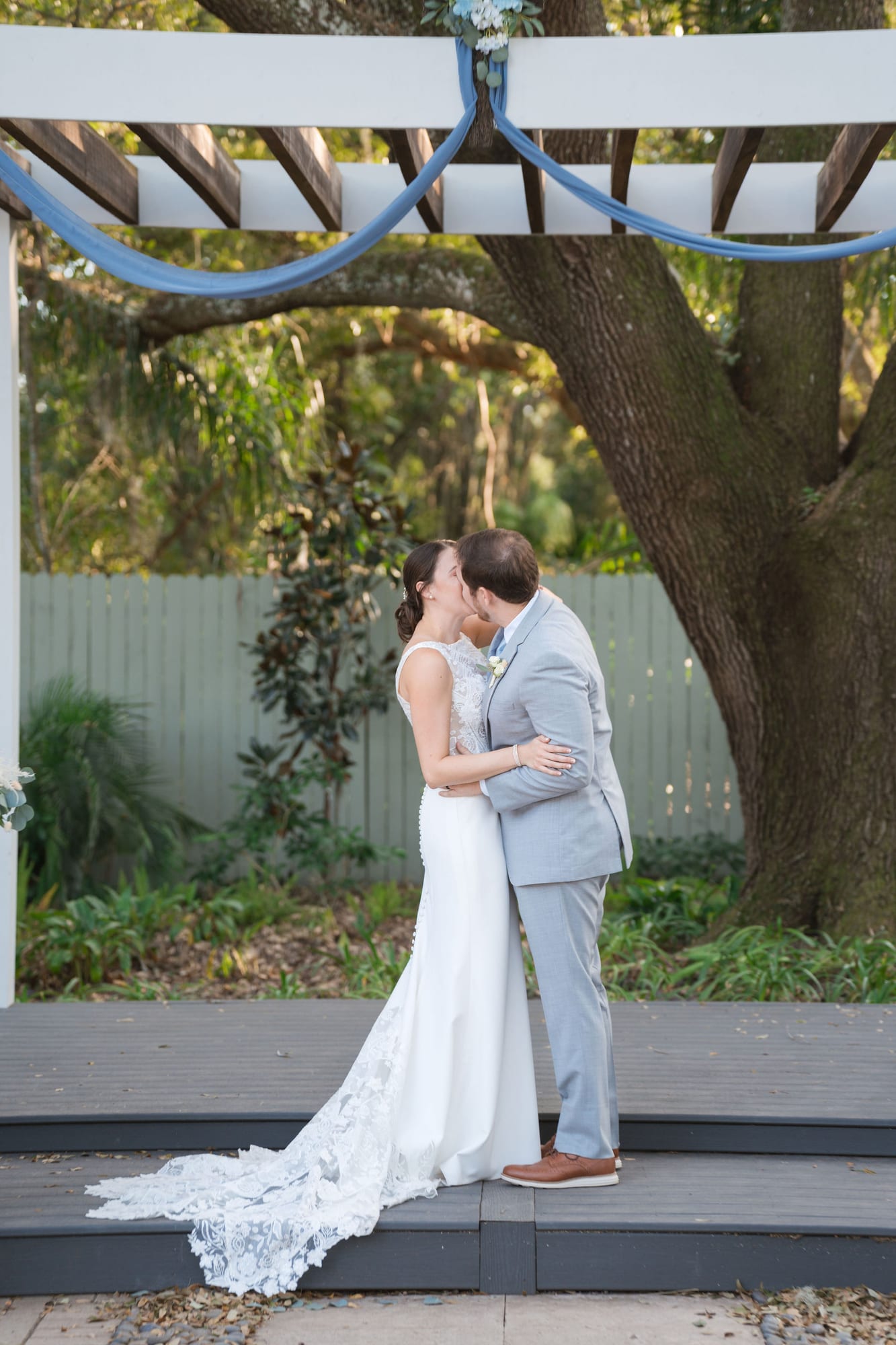 Bride and groom share their first kiss under the draped pergola