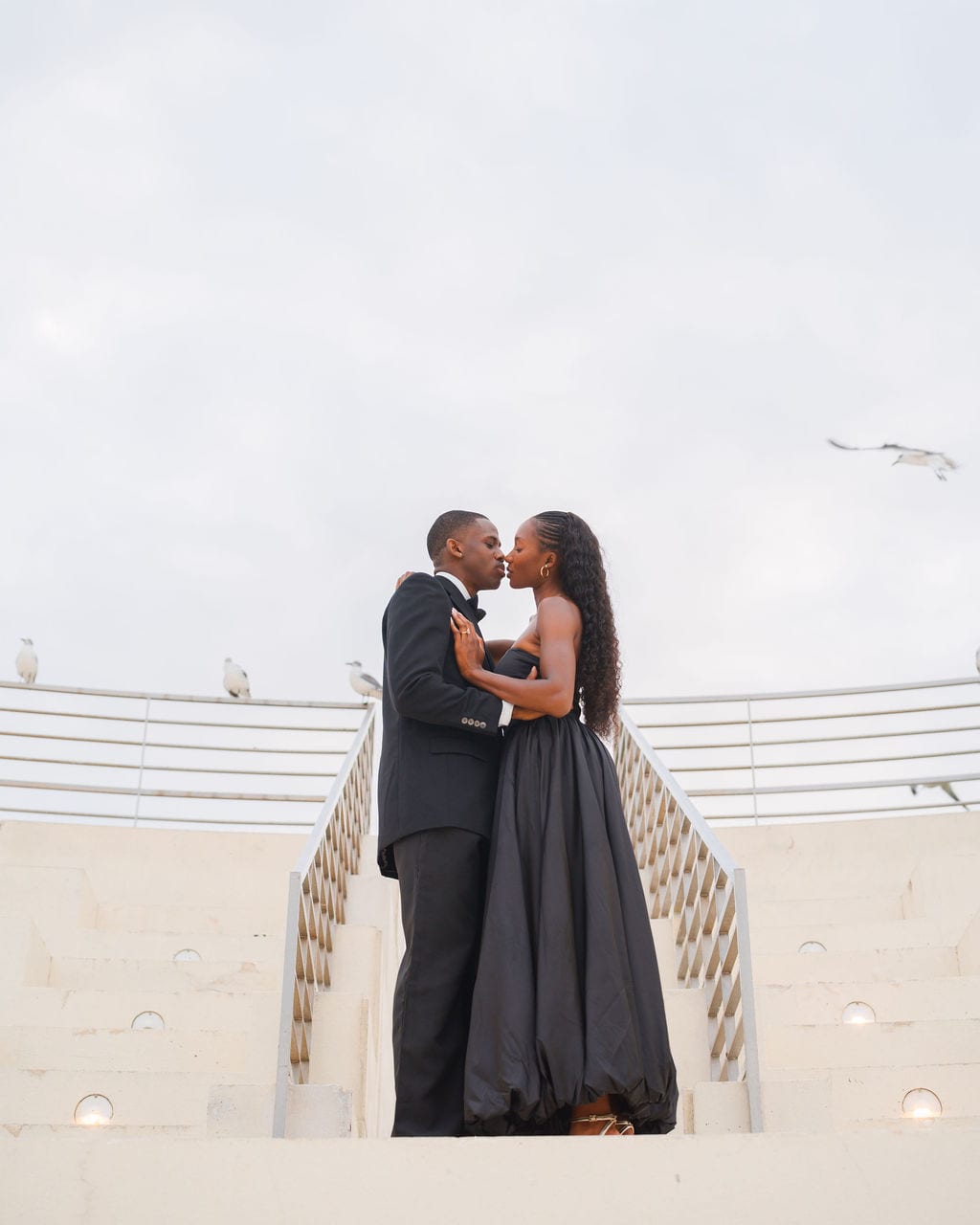 Couple kissing on the white amphitheater steps at a Tampa waterfront park during their engagement session