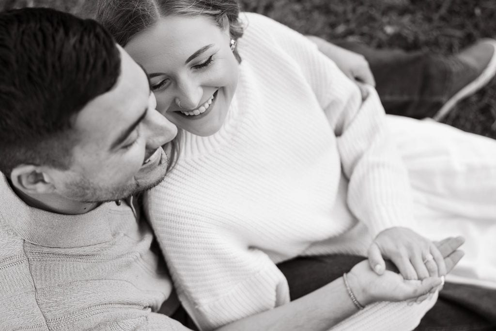 Black and white photo of a couple laughing with the engagement ring visible