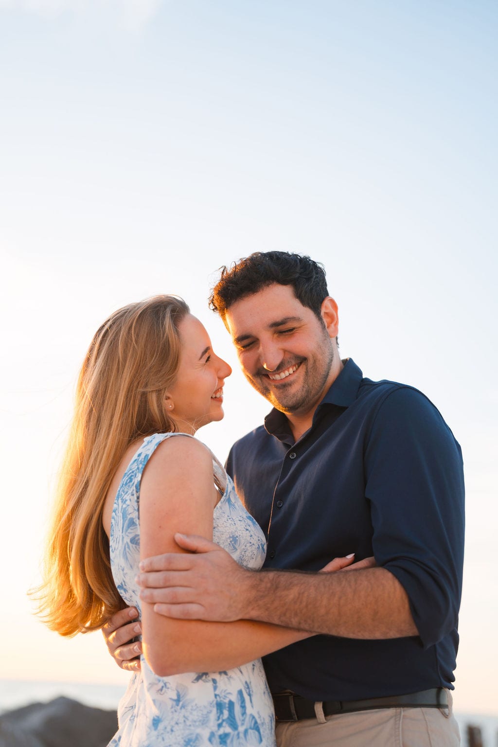 Engaged couple laughing during a golden hour engagement session on a Tampa beach