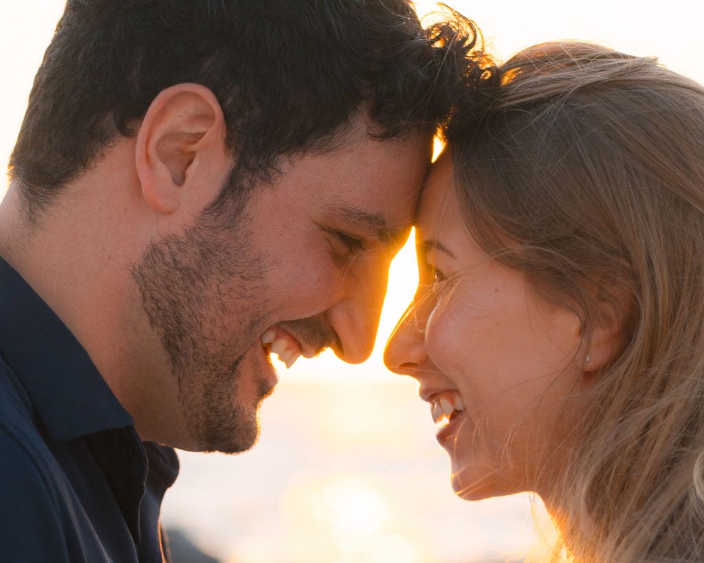 Couple forehead to forehead laughing during a sunset engagement session near Tampa