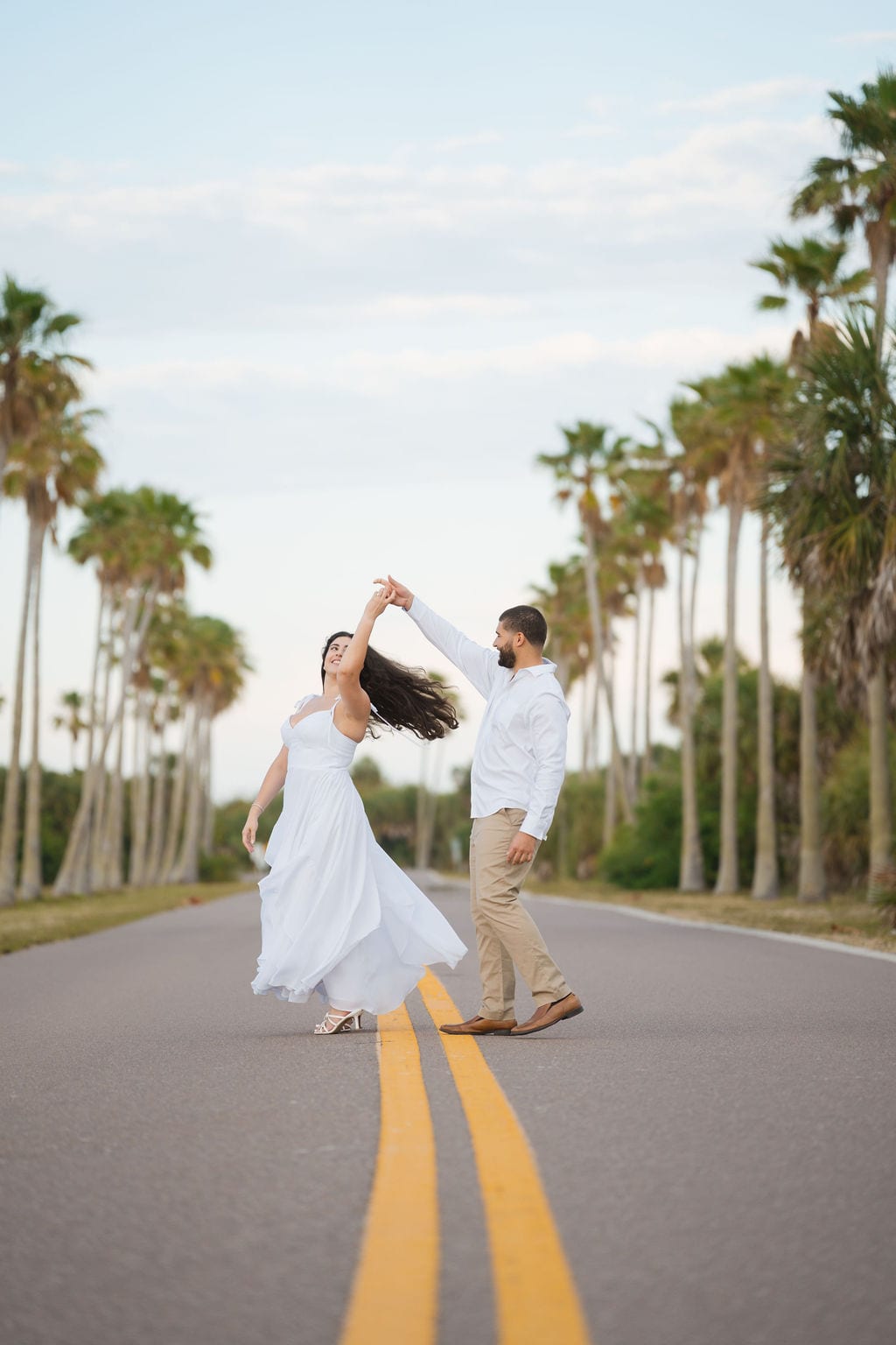 Couple twirling on a palm lined road during a Tampa engagement session