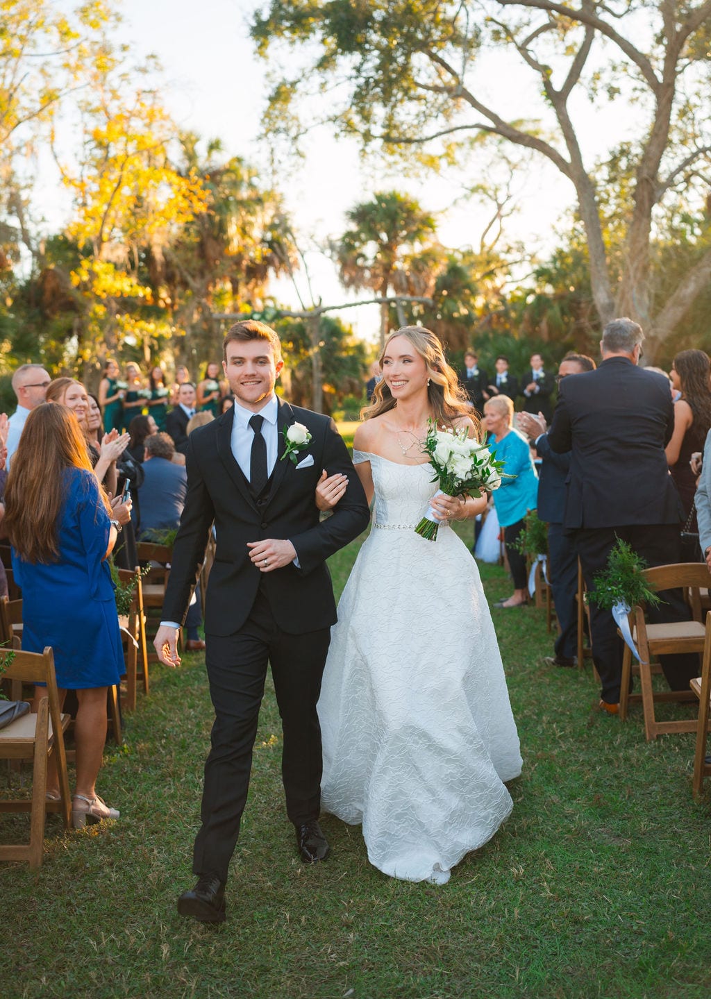 Bride and groom walking down the aisle after a ceremony under oak trees in Florida