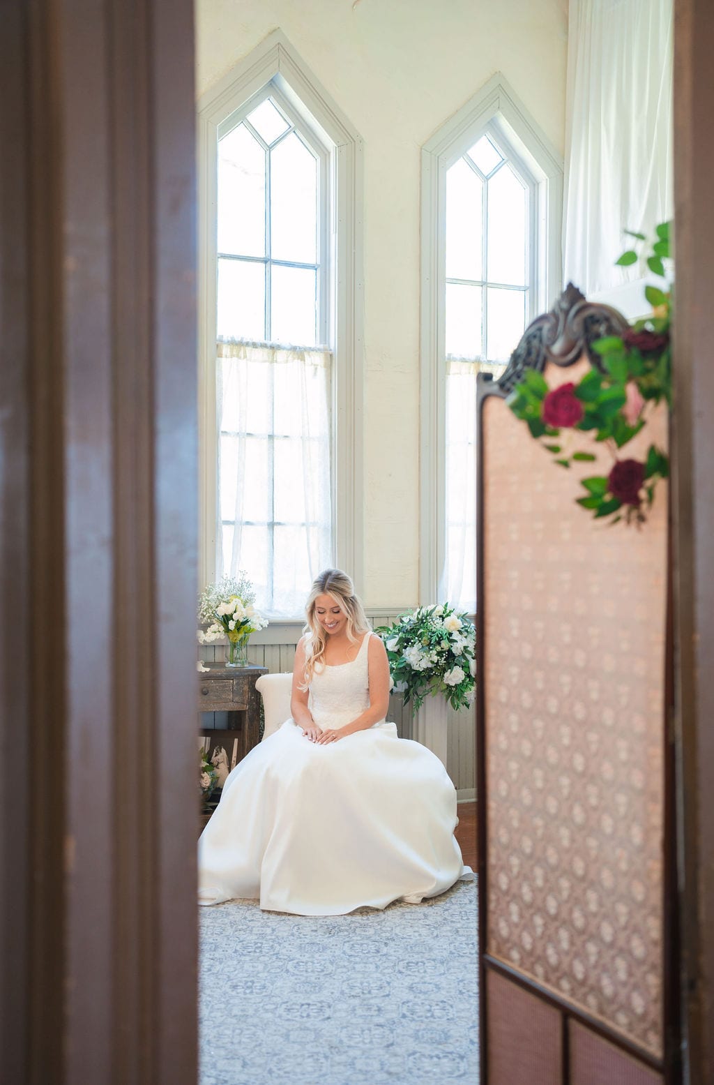 Bride seated in a bridal suite with arched windows before a Florida wedding
