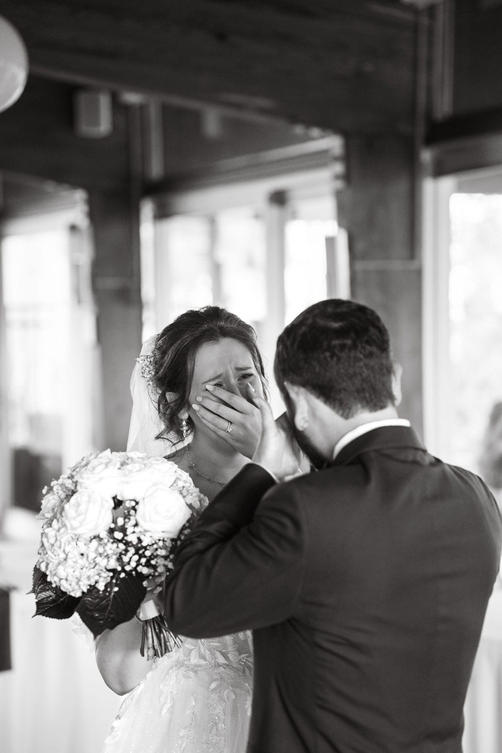 Groom wiping his bride's tears during a first look, black and white