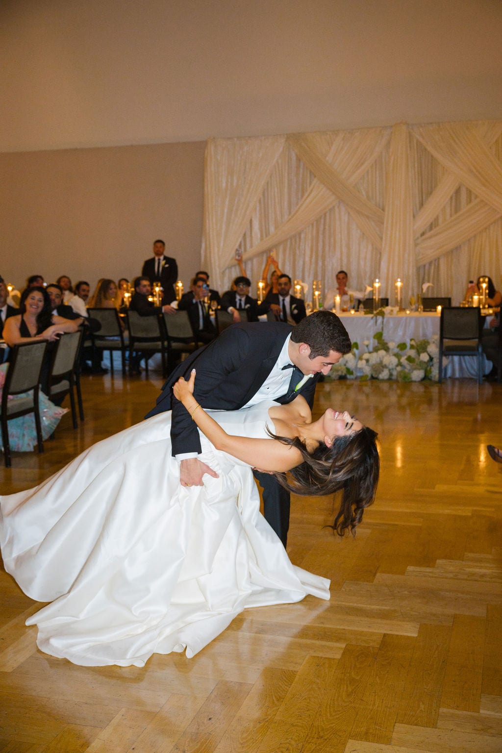 Groom dipping bride during a first dance at an indoor ballroom reception