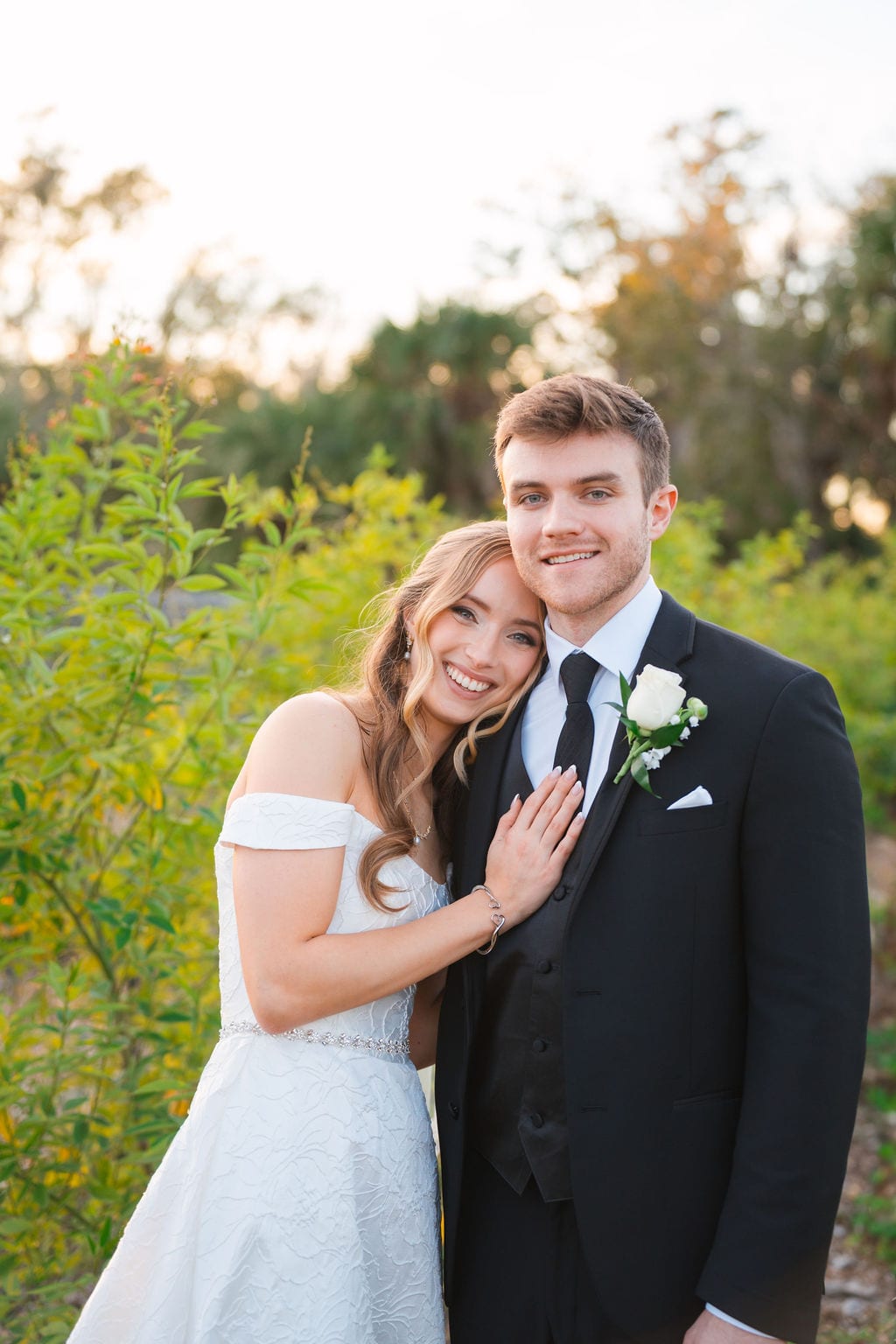 Bride and groom smiling in golden hour light surrounded by Florida greenery